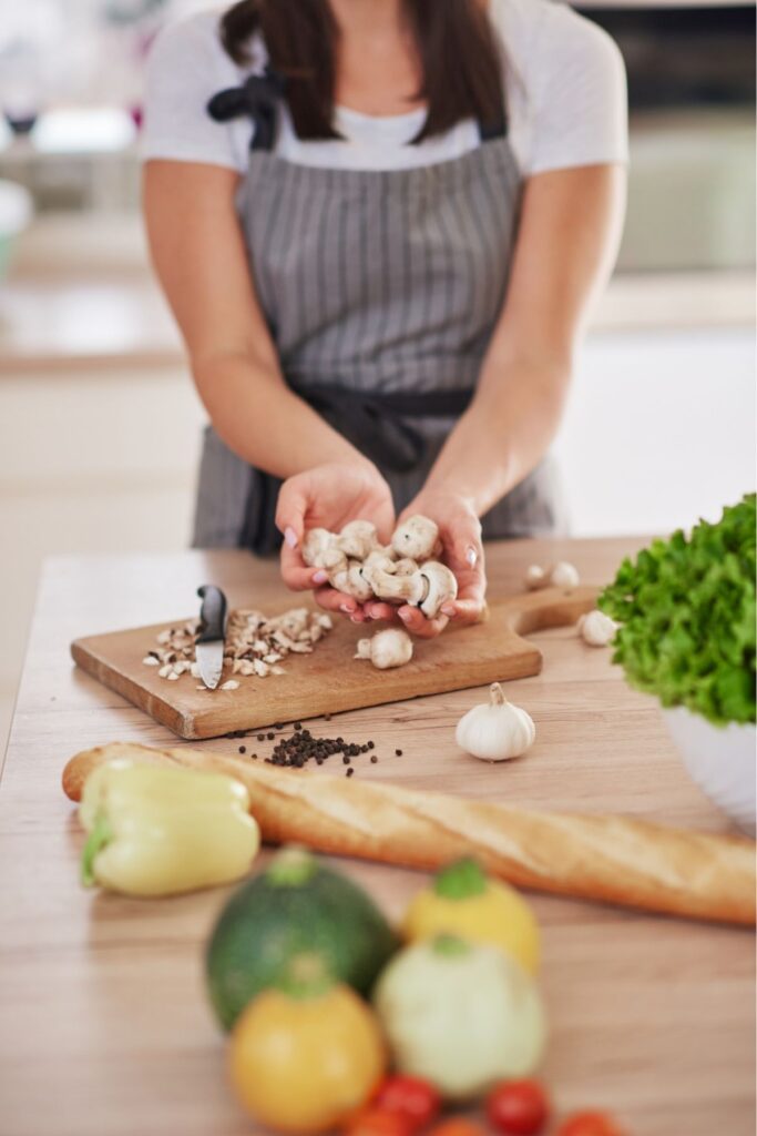 A woman cutting food to make dinner.