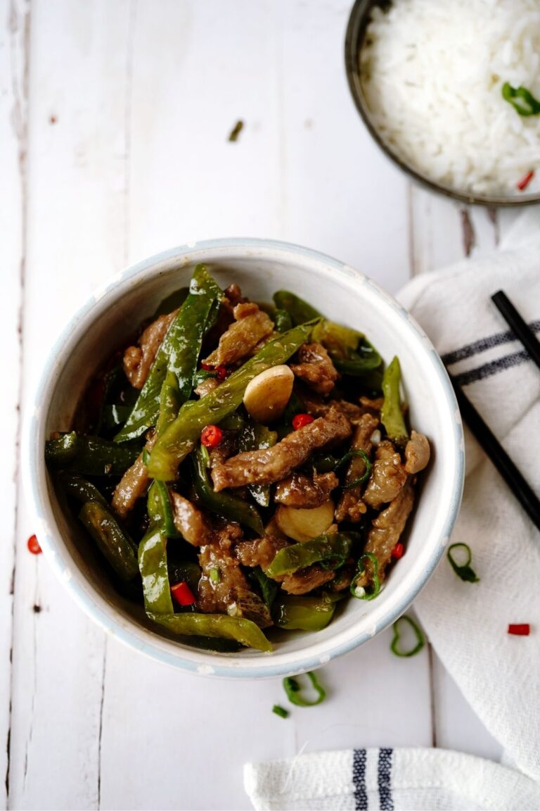 A bowl of rice with asparagus beef on top of the rice.