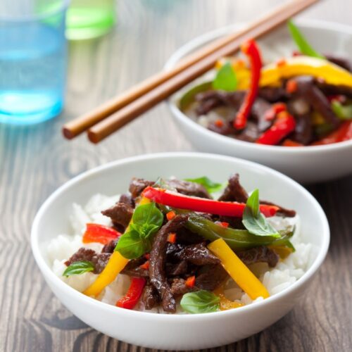 A bowl of rice topped with Beef stir fry.