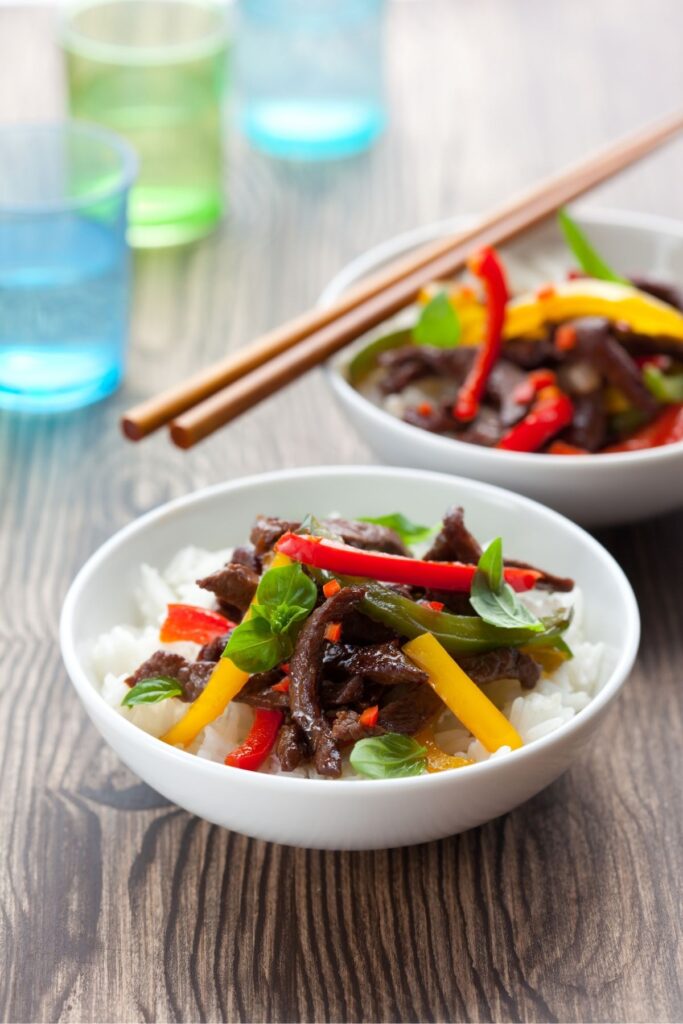 A bowl of rice topped with Beef stir fry.