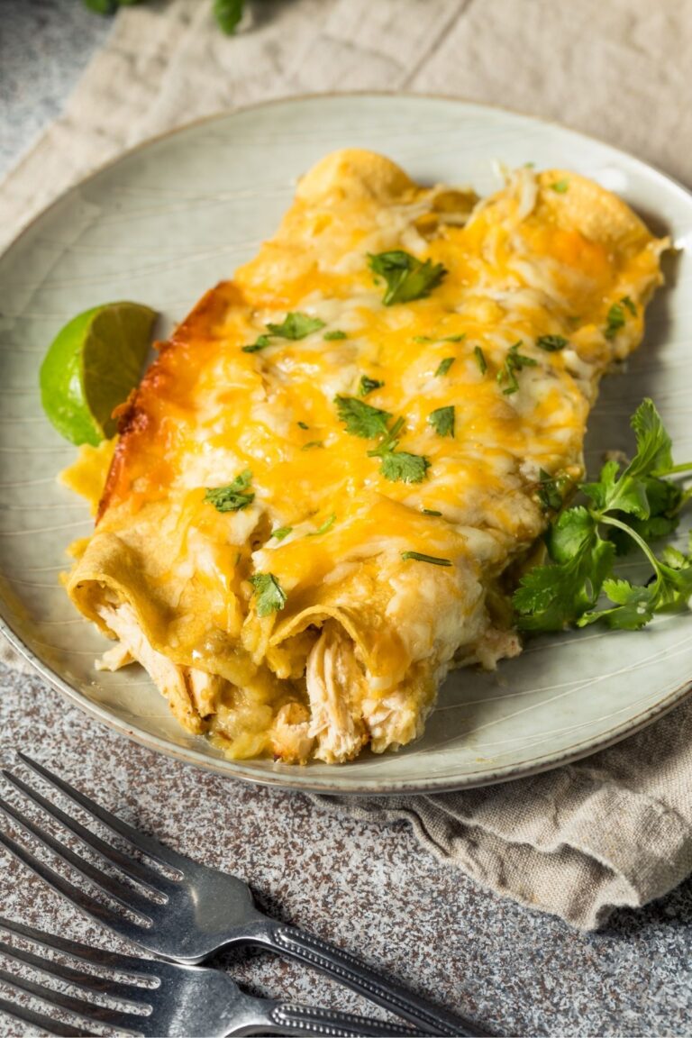 Chicken Enchiladas with green sauce on a plate with a fork next to it.